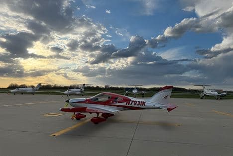A red and white Bristell on the ramp at sunset