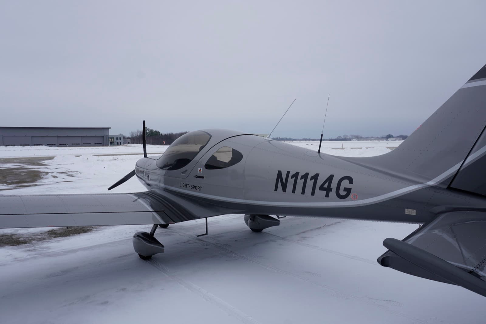 The silver Bristell N1114G in profile on a snow lined ramp
