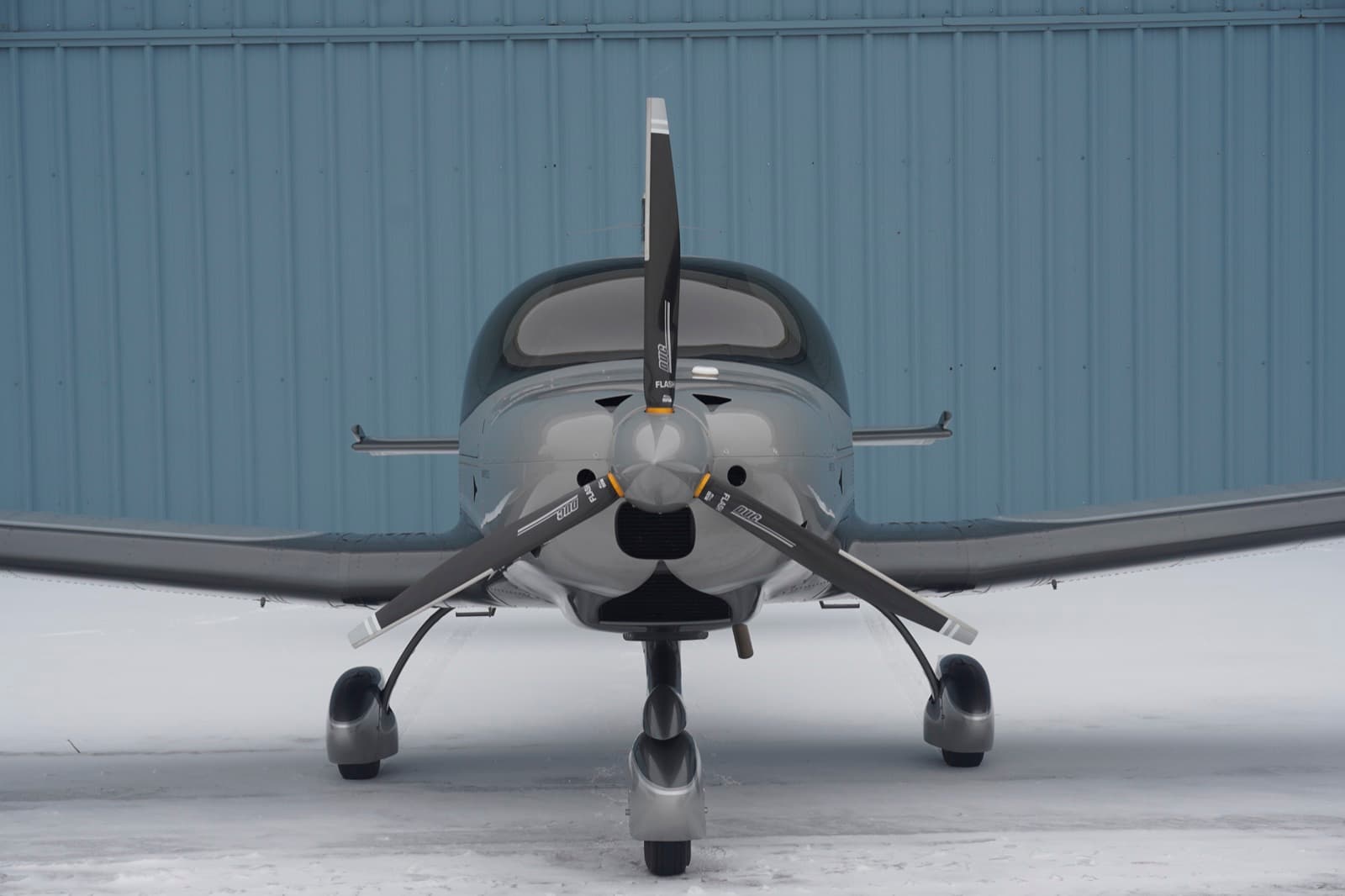 A silver Bristell head on against the hangar wall