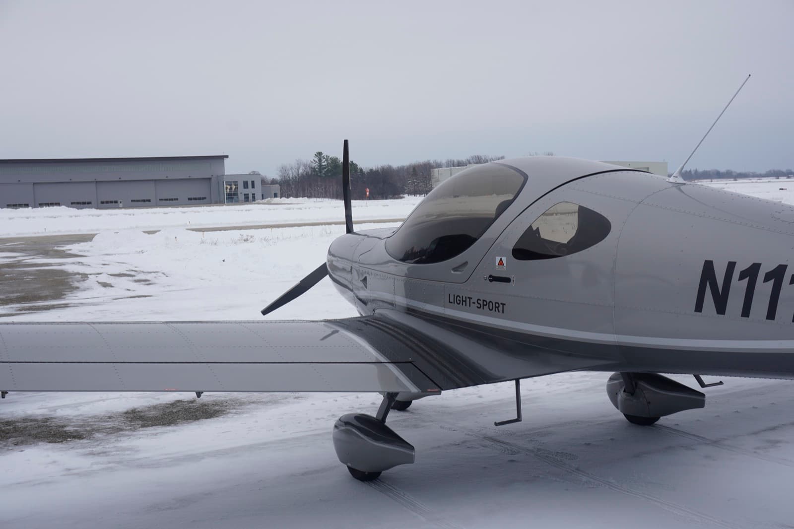Nose and propeller of a silver Bristell on a snow covered ramp