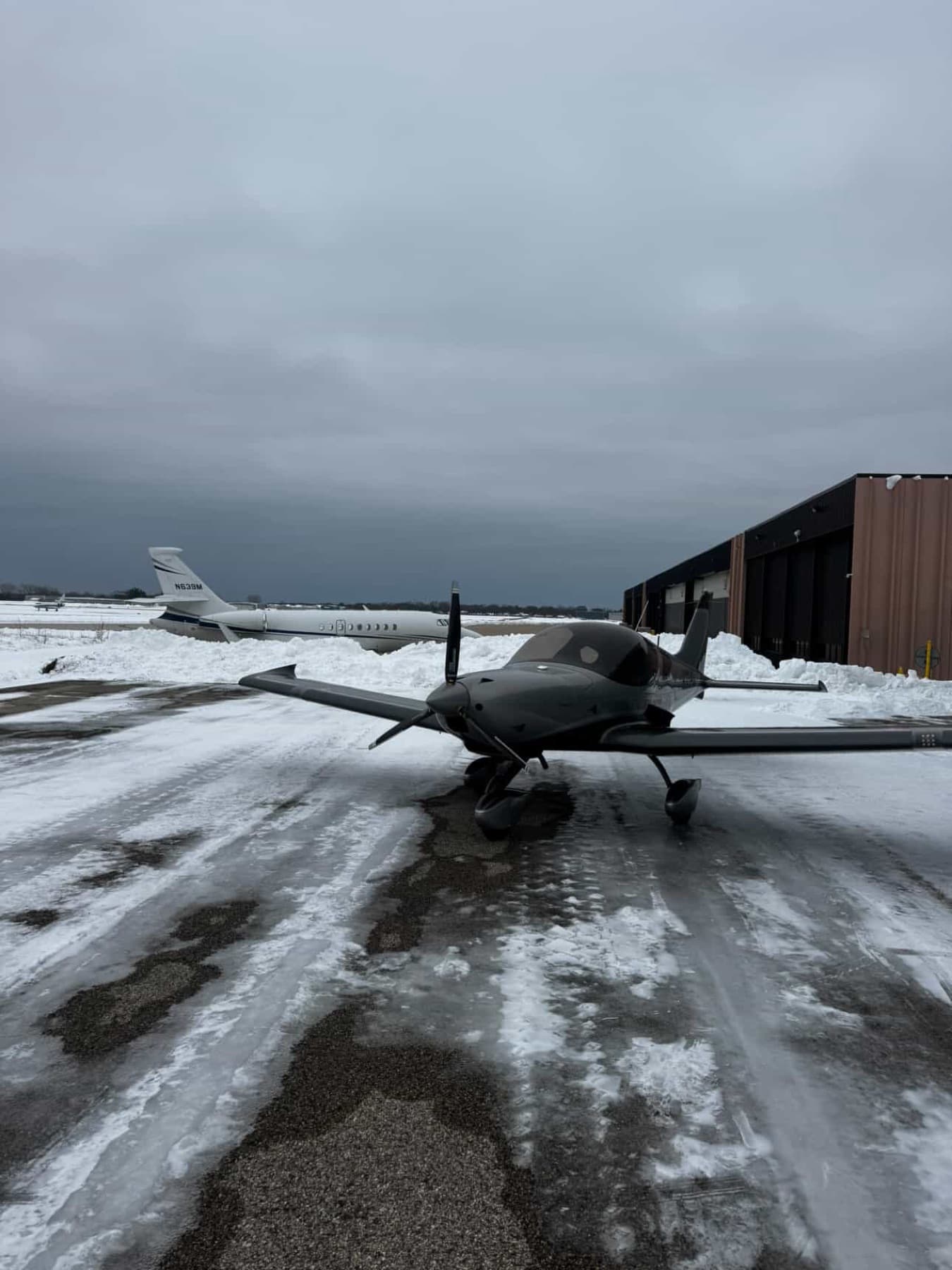 A silver Bristell on a wet, snow lined ramp