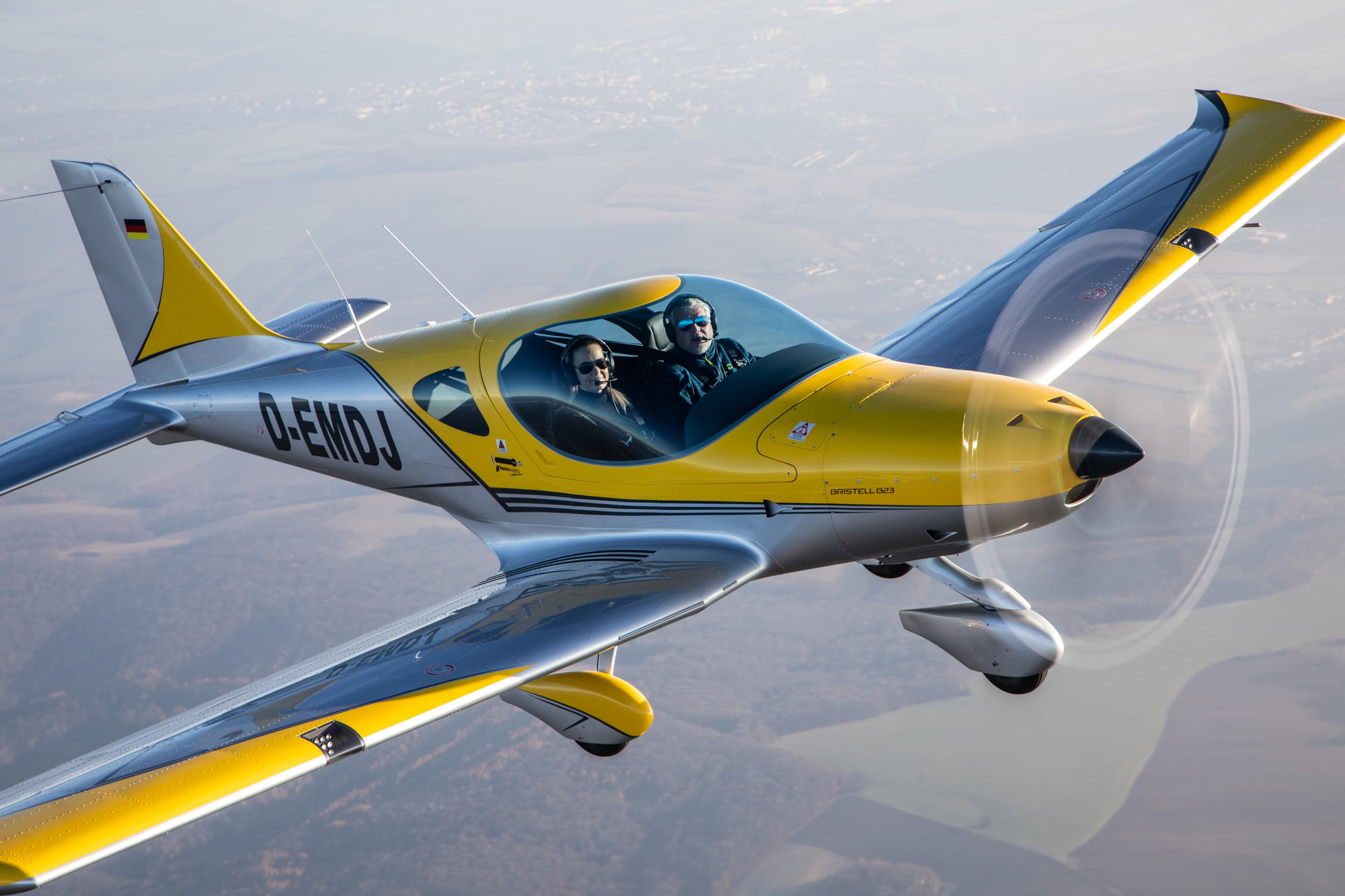 Yellow Bristell B23 in flight with an instructor and student on board
