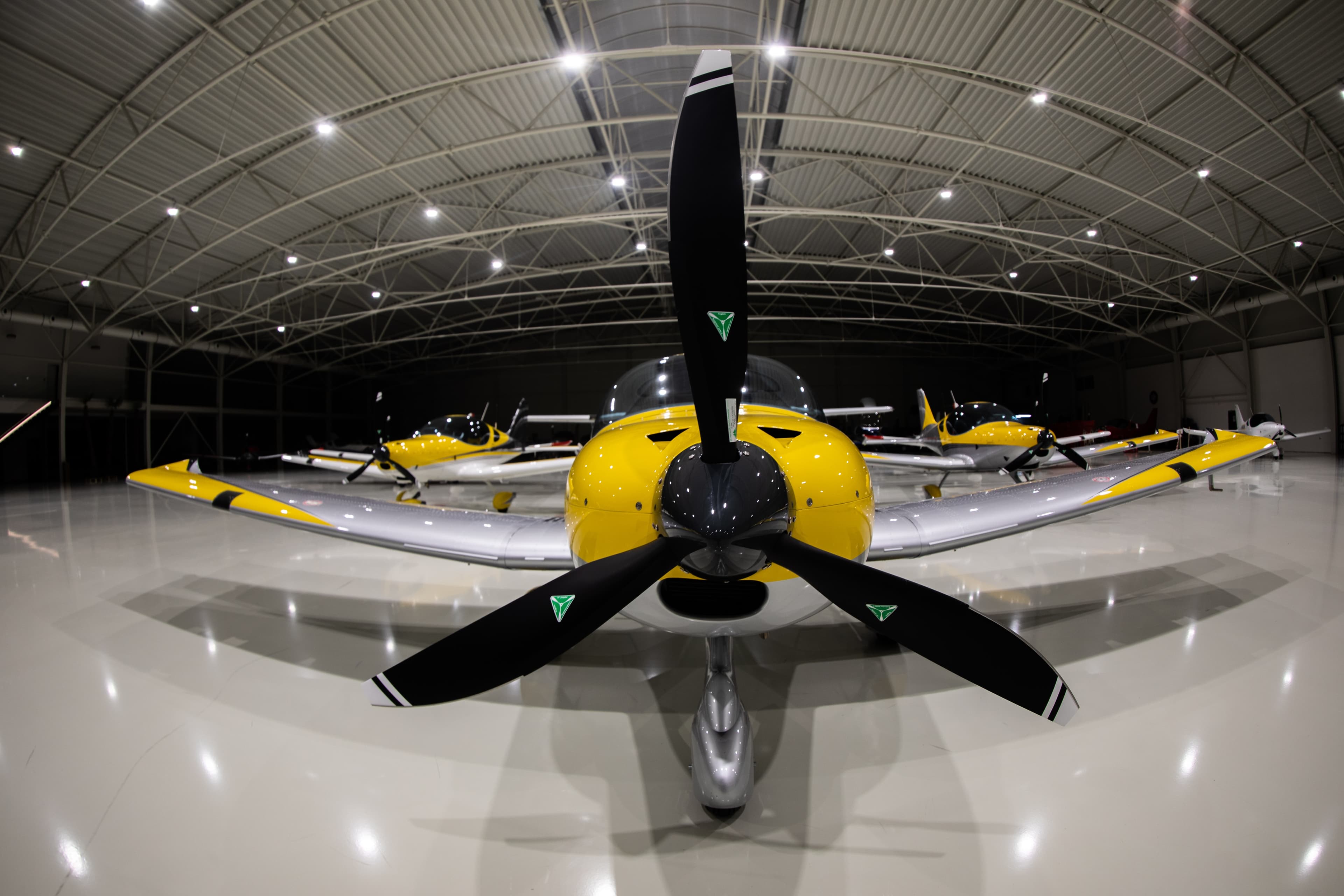 Yellow Bristell parked in the hangar, propeller and spinner head-on
