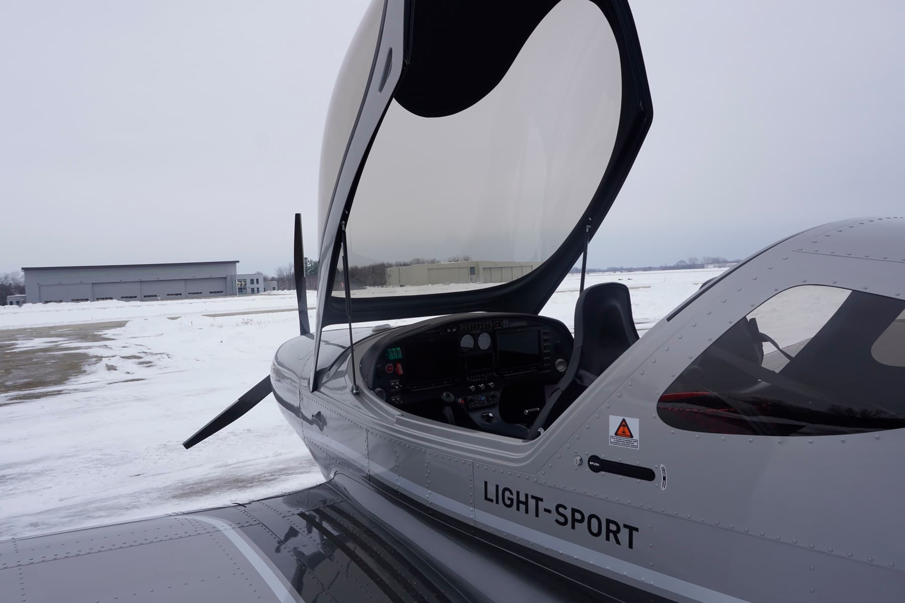Open canopy of a Bristell showing the glass cockpit on a snowy ramp