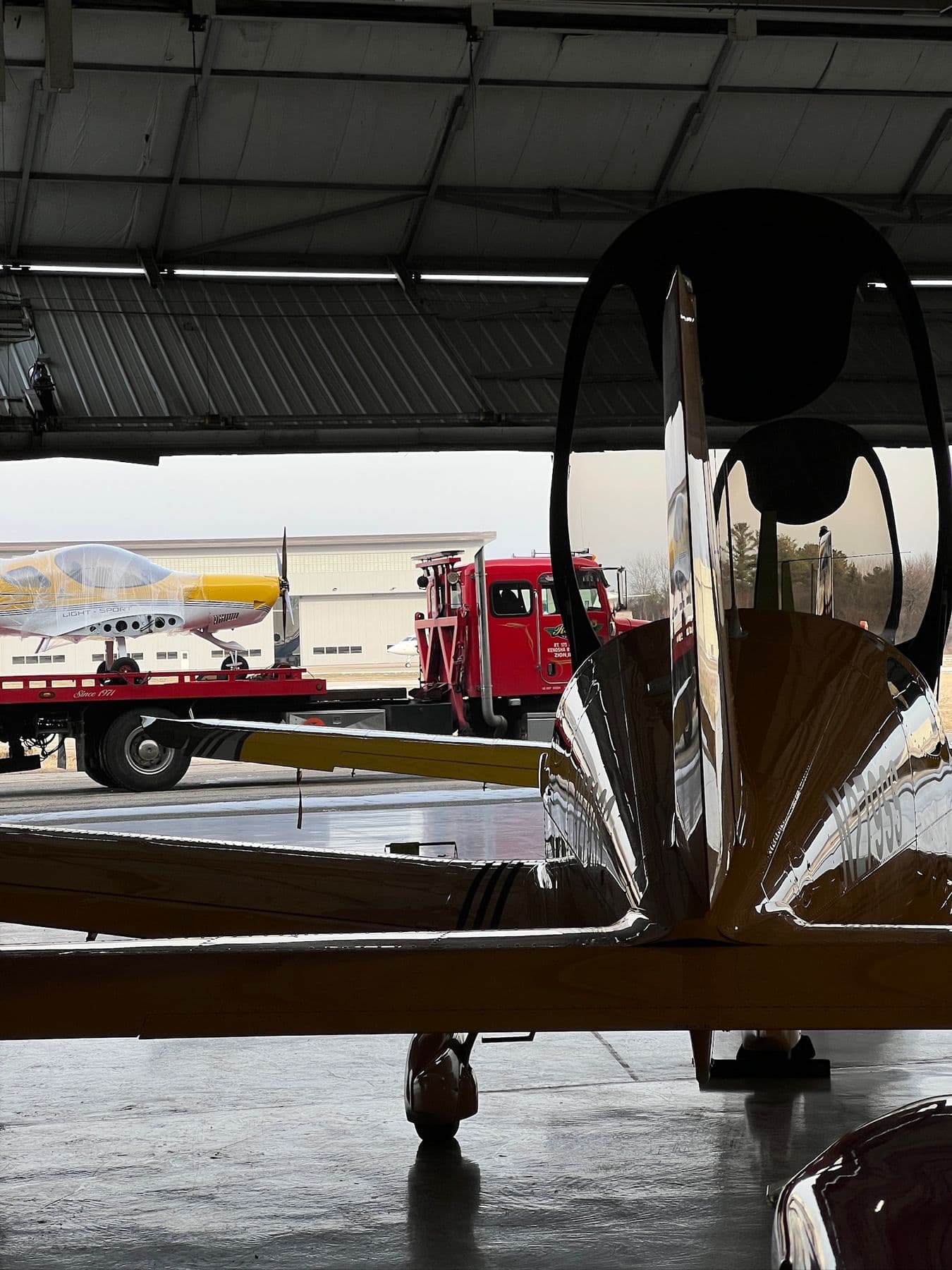 A Bristell on a flatbed truck inside the hangar