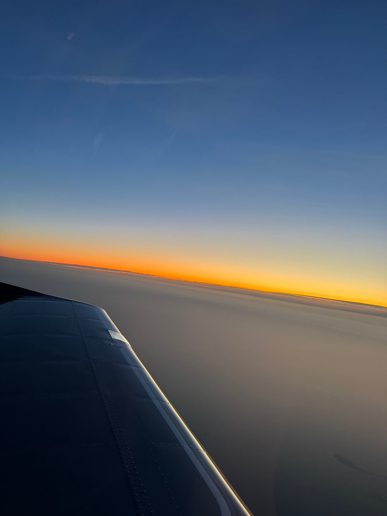 Sunset on the horizon seen over the wing in flight