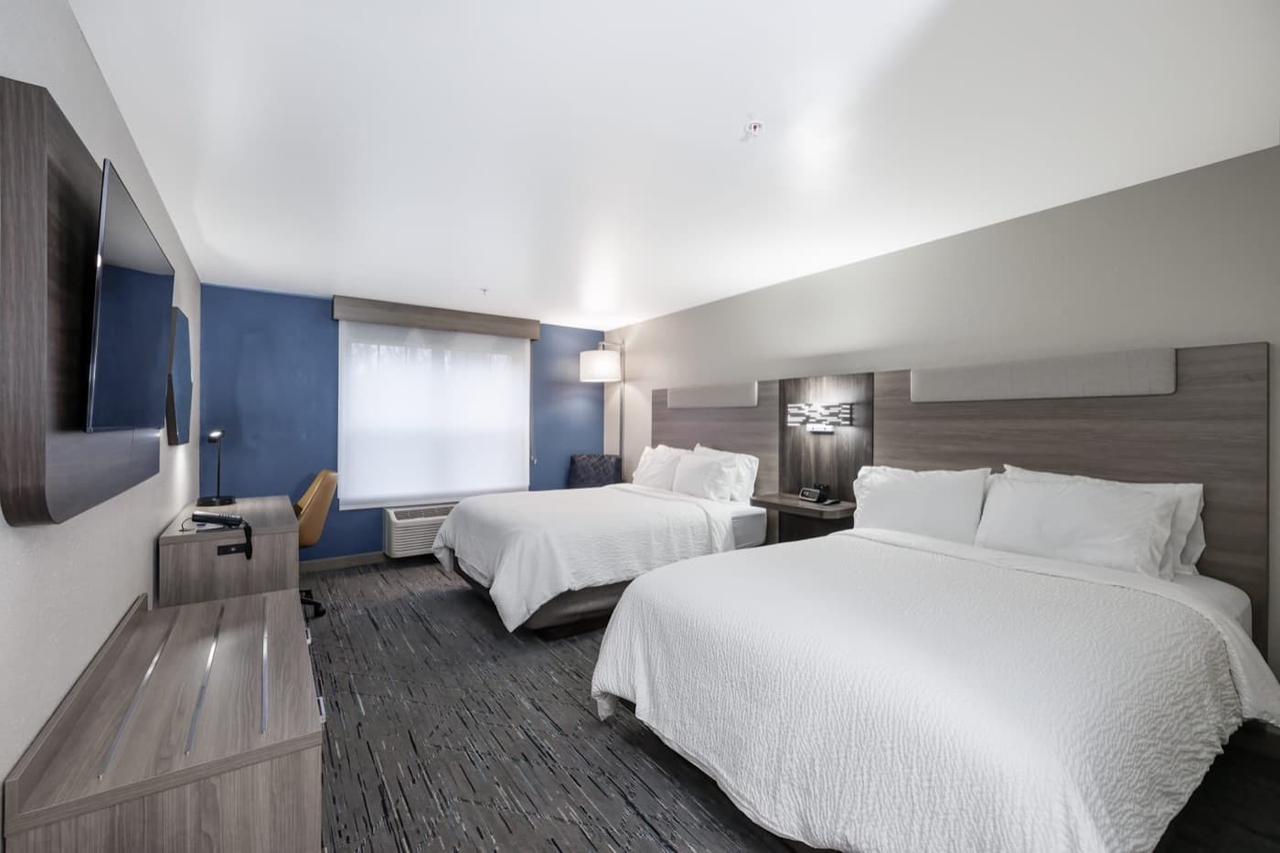 Hotel room with two queen beds and a wall-mounted television