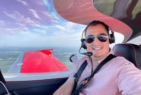 Dragan Lazic in the cockpit, headset on, with the wing and horizon behind him